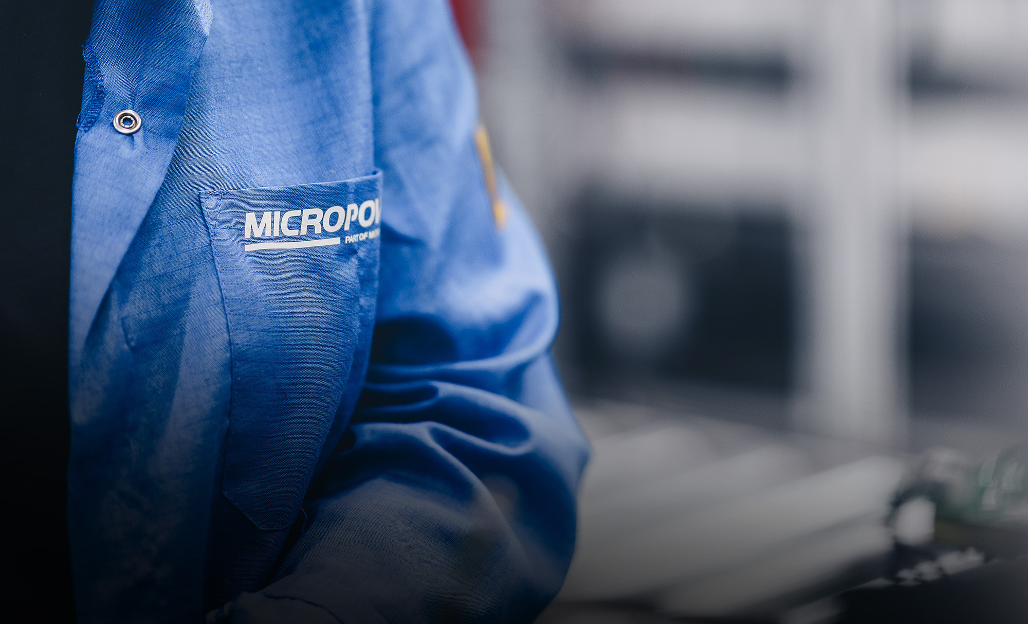 The Micropower logotype exposed on the chest-pocket of the blue overall, on one of Micropowers engineers.