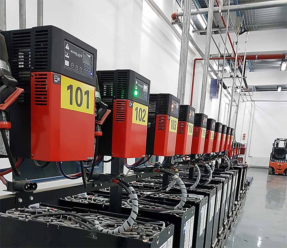 A long row of large, red and yellow AGV-batteries  in a battery exchange room in a modern environment
