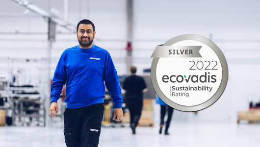 Happy employee in Micropower's battery factory with Ecovadis logo